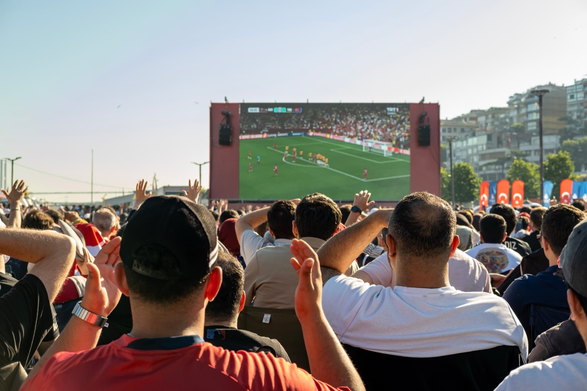 Crowd watching a match on a large outdoor screen