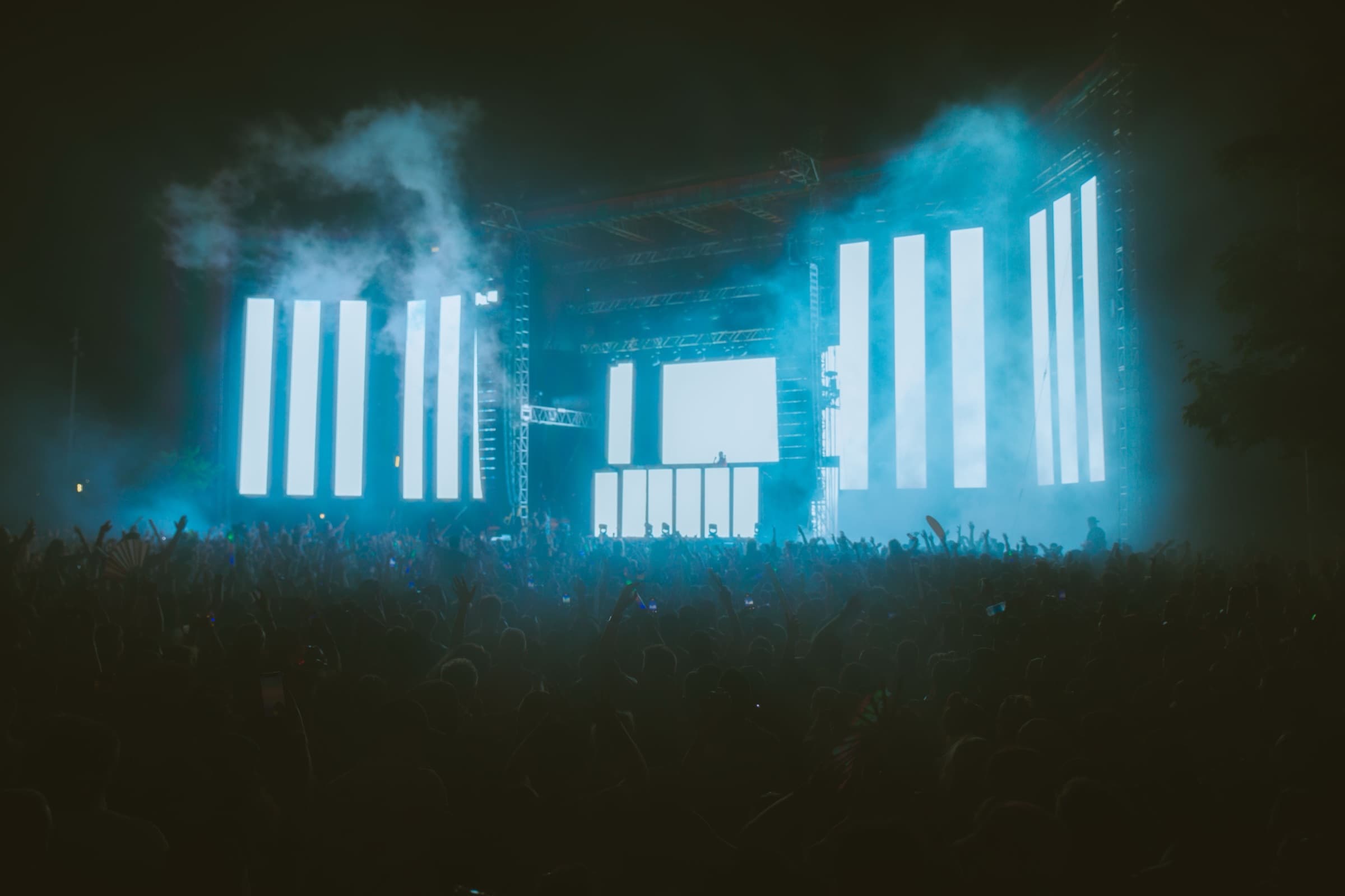 Night festival stage with large LED screens and a crowd