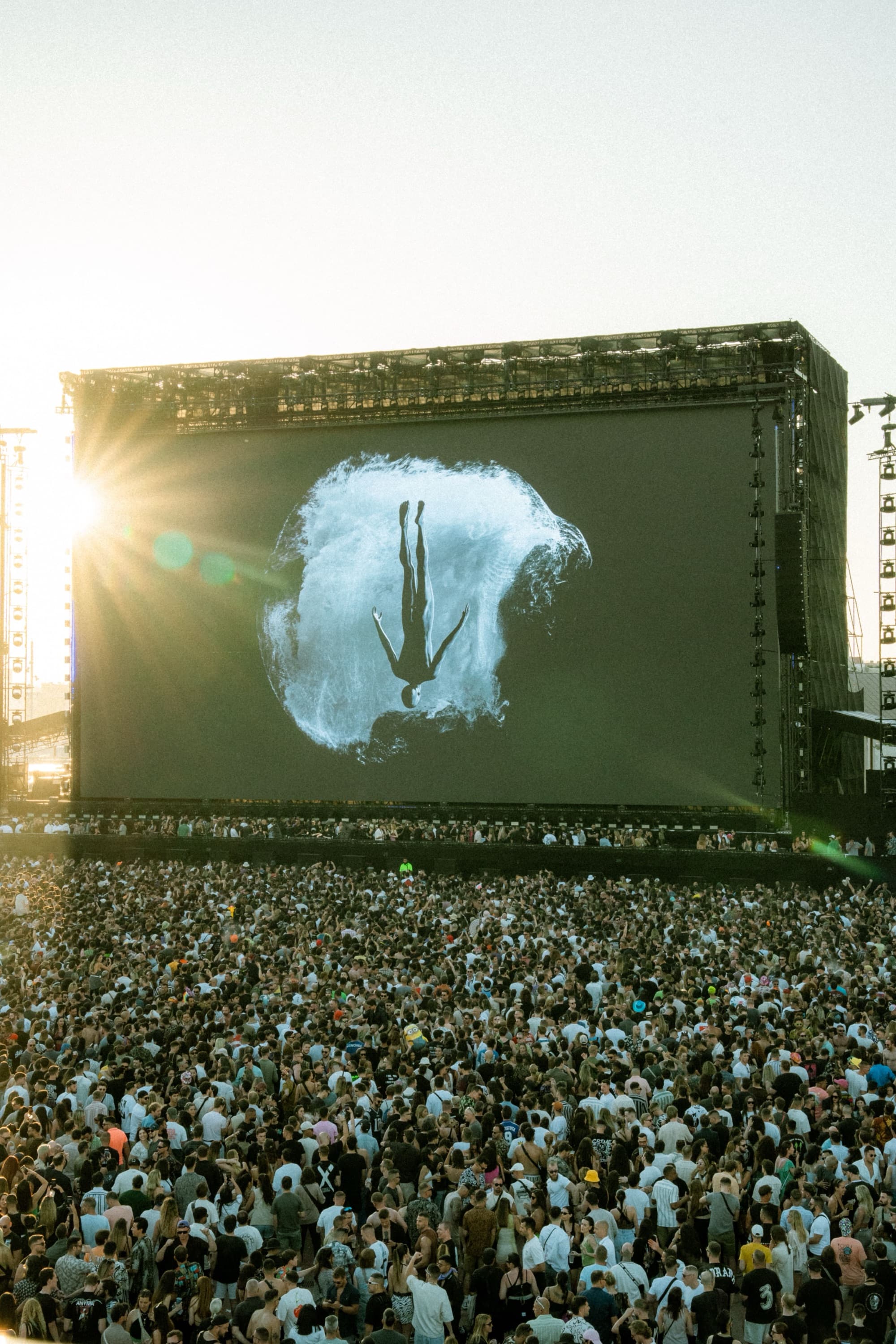 Large daytime festival stage in front of a huge crowd